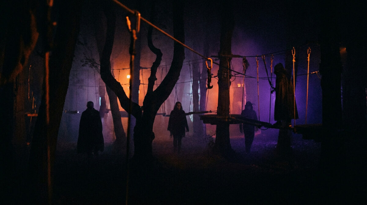 Parcours d'accrobranche nocturne dans une forêt hantée avec éclairages violets et brume