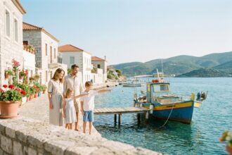 Famille en vacances découvrant un village côtier méditerranéen avec barques colorées et maisons blanches